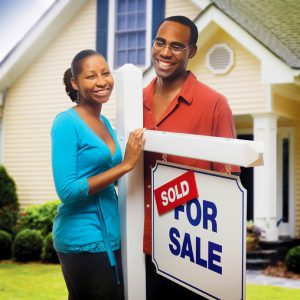 African American couple in front of home for sale.