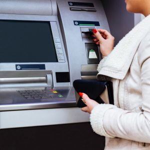 Woman's hand puts credit card into ATM, close up